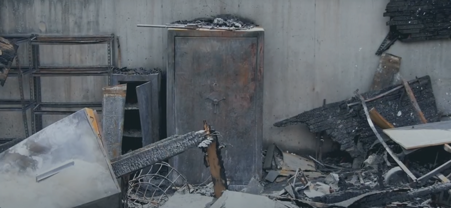Damaged safe and debris against a concrete wall